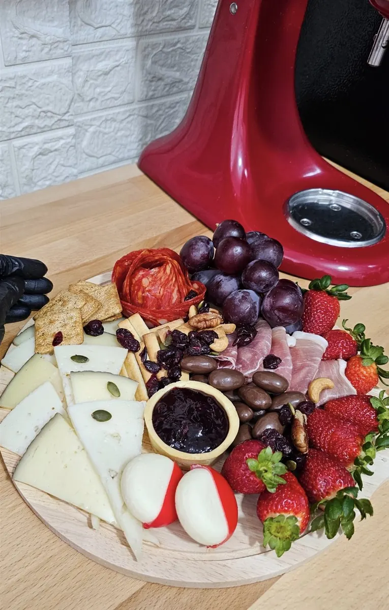 Tabla de charcutería con salami, quesos, uvas y frutos secos en preparación