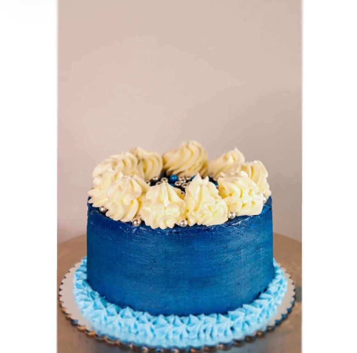 Torta azul con rosetones de crema y perlas plateadas