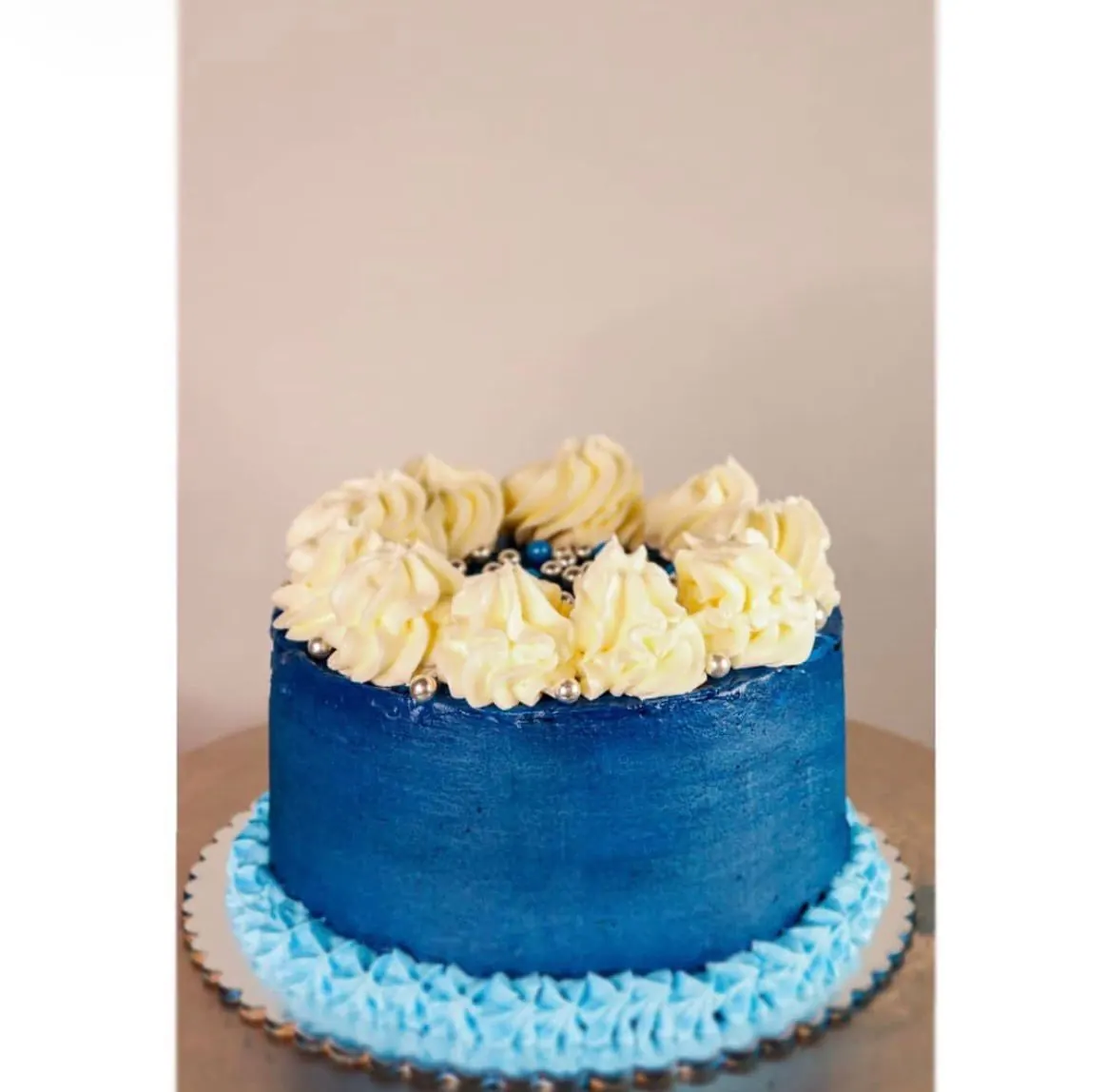 Torta azul con rosetones de crema y perlas plateadas
