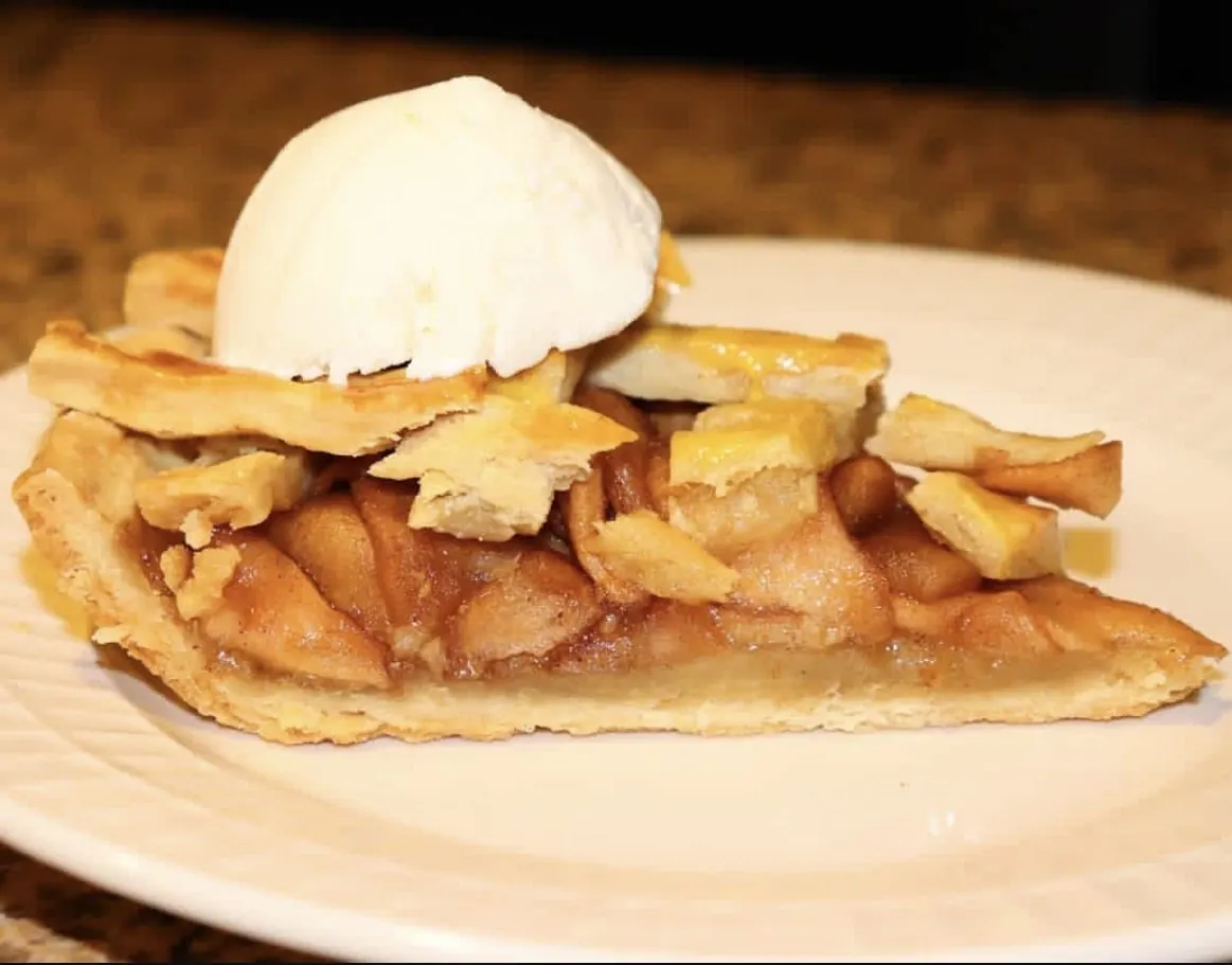 Porción de tarta de manzana con bola de helado de vainilla